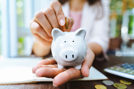 Image of a woman putting money in a piggy bank