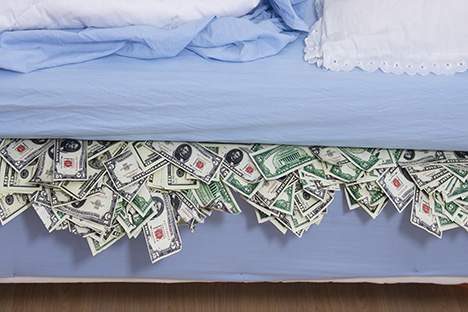 Image of piles of cash under a mattress
