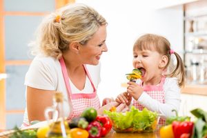 Mother feeding daughter vegetables