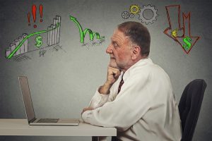 a man sitting at a table and looking at a stock chart