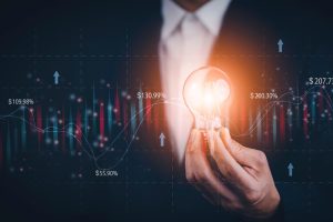 Businessman holding light bulbs, new ideas with of Stock market or forex trading graph and candlestick chart suitable for financial investment, Economy trends background for business idea stock.