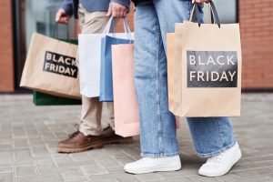 Two people holding shopping bags that say “Black Friday” on the side