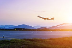 A passenger plane taking off with mountains in the background