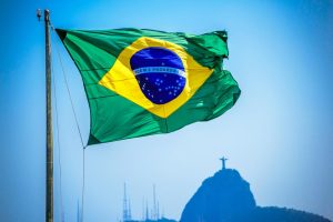 The Brazilian flag flying with the Christ the Redeemer statue in the distance