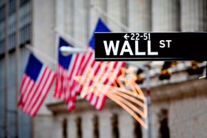 The “Wall Street” sign in New York in front of several American flags