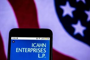 The Icahn Enterprise logo on a smartphone in front of an American flag