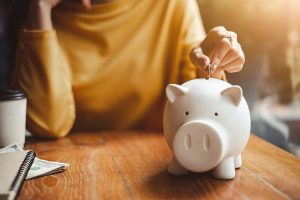 A woman putting money into a piggy bank