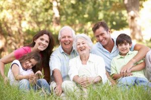 A multigenerational family sitting in the grass together and smiling