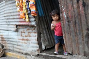 A little Nicaraguan girl standing in the doorway of a run-down house