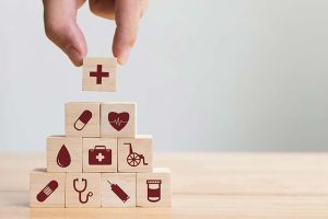 A hand arranging wooden blocks with healthcare-related logos