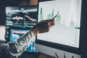 A hand pointing at a screen showing a stock chart