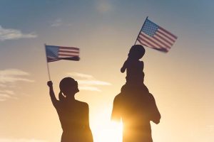 A silhouette of a family waving two American flags