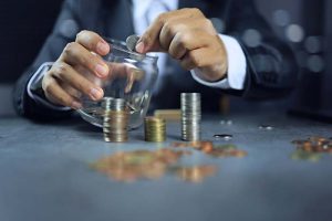 An investor dropping coins into a glass jar