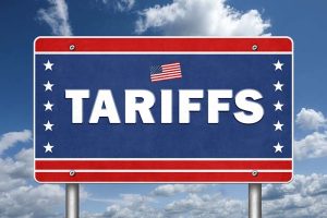 A red, white, and blue road sign with an American flag at the top and “TARIFFS” in bold letters