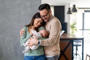 A young couple holding a baby and smiling