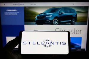 The Stellantis logo on a smartphone in front of a laptop showing the company’s website