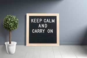 A letter board that says “KEEP CALM AND CARRY ON”