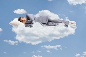 A man in pajamas peacefully sleeping on a cloud
