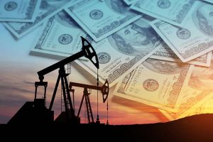 Two oil pumps photographed at sunset, with U.S. dollar bills in the background