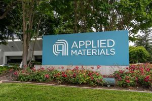 A sign displaying the logo of Applied Materials in front of a building
