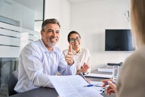 A smiling couple sitting in their financial advisor’s office