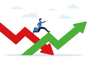 A businessman holding a briefcase and running on top of a green up arrow and a red down arrow