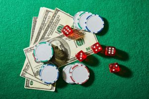 A pile of several $100 bills, poker chips, and dice