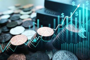 A rising stock chart superimposed over a pile of coins on a desk