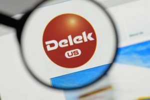 The logo for Delek US Holdings on a screen under a magnifying glass