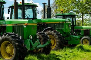 Three John Deere tractors sitting in a field