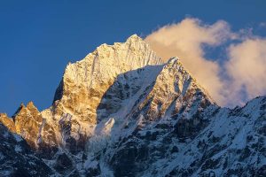 A snow-capped mountain with clouds in the background