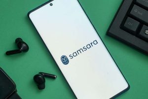 The Samsara logo on a smartphone next to a computer keyboard and a pair of earbuds