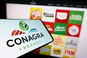 The Conagra Brands logo on a smartphone in front of a grid of the company’s brands