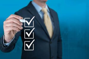 A businessman holding a pen and checking off three boxes