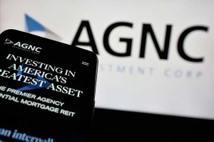 A close-up of a smartphone reading “Investing in America’s greatest asset” with the AGNC Investment Corp. logo in the background