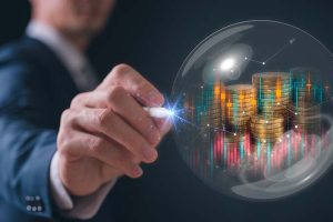 A businessman holding a pin up to a bubble with coins and stock charts inside