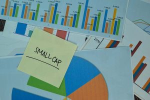 A yellow sticky note with “small caps” written on it, next to several charts