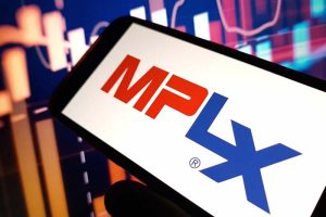 The MPLX logo on a smartphone with stock charts in the background