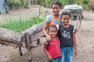 Three smiling children in rural Nicaragua with their arms around each other