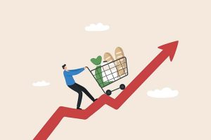 A graphic of a shopper pushing their shopping cart while standing on a red, upward-facing arrow