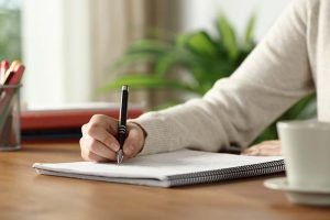 A close-up of a student’s hand as they write notes in a notebook