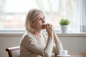 A retirement-age woman sitting and appearing to be stressed or thoughtful