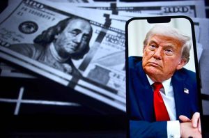 An image of President Trump on a smartphone in front of several $100 bills
