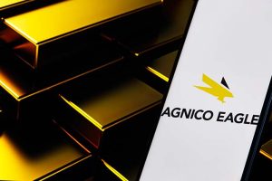 The Agnico Eagle Mines logo on a smartphone next to several gold bars