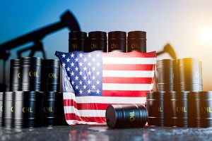 Several stacks of black oil barrels with an American flag draped over them