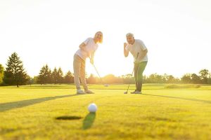 A retirement-age man and woman celebrating a golf putt