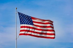 An American flag waving against a light blue sky