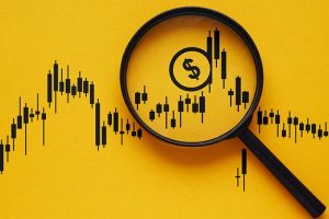 A portion of a stock chart on a yellow background under a magnifying glass