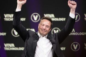 Elon Musk smiling with his arms raised